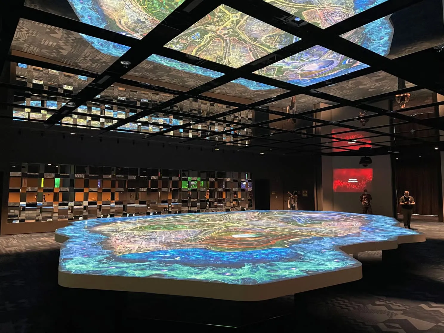 An illuminated relief map of the country in a hall lined with ceiling screens