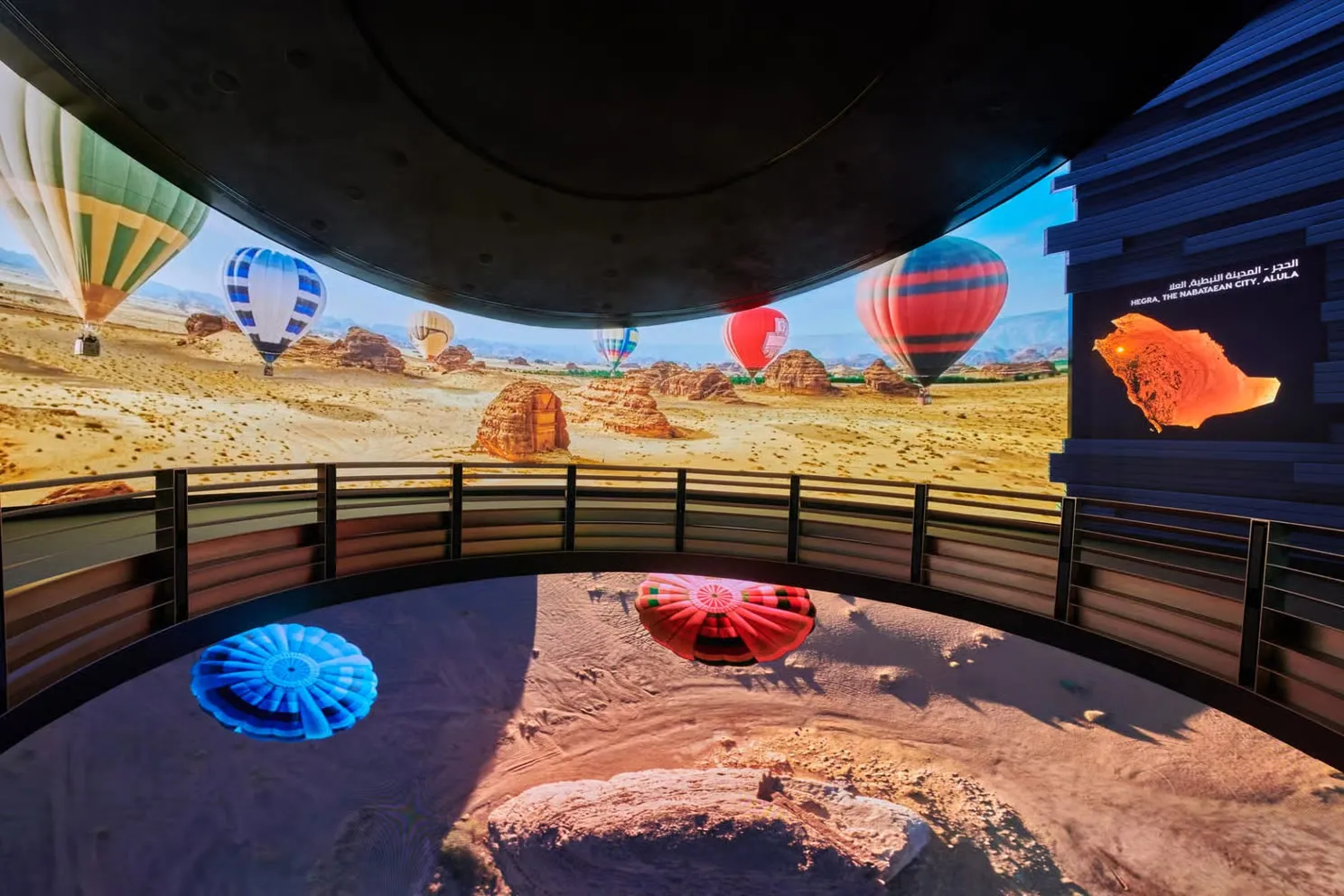 Hot-air balloons over the desert on a curved panoramic screen, with light projected on the floor